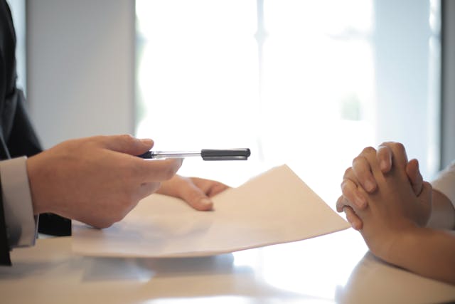 A man and woman sitting at a table with a pen and paper, discussing experiture marketing reviews