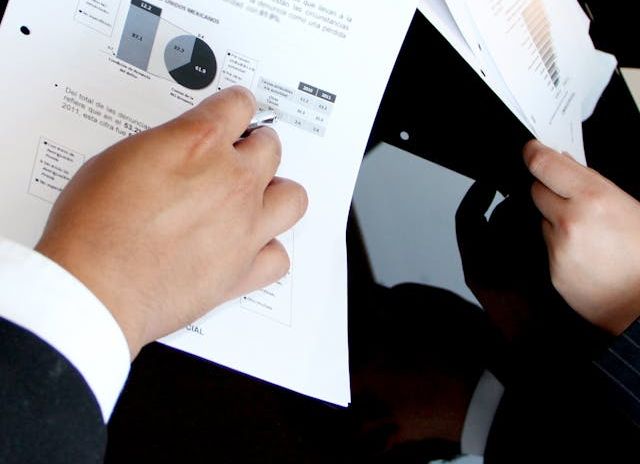 Two professionals in suits holding papers, one person with a pen. Marketing Research