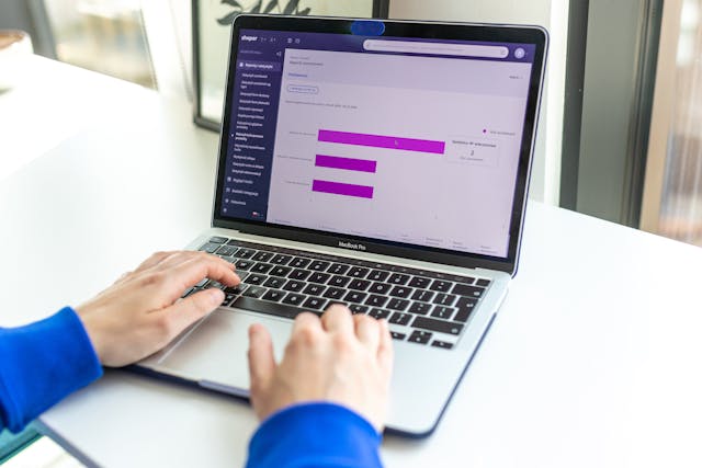 A man using a laptop displaying a purple bar chart. Represents data analysis on Shopify Plus